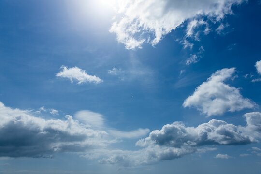 Fototapeta Large cumulus clouds are floating across flat design sky with sunlit highlights and wispy streaks