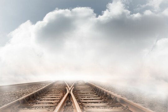 Fototapeta Train tracks leading over the cloudy horizon