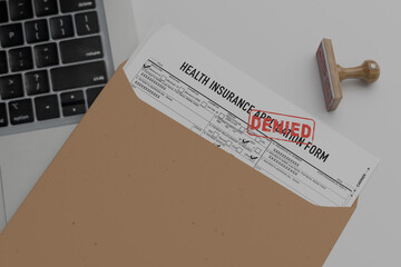 Denied health insurance application form on the table. Document with denied stamp put on the ...