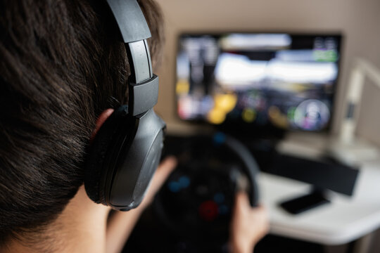 Person gaming with steering wheel controller in home setup for virtual simulation