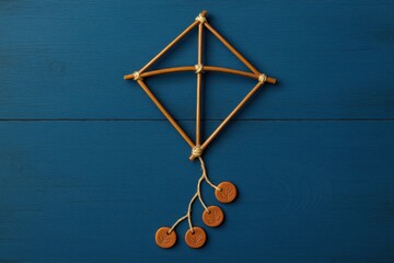 Palm Thread Kite Frame with Clay Tail Rings on Blue Wooden Background

