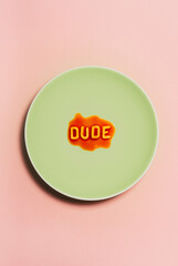 The word Dude in spaghetti on a pastel green plate. 