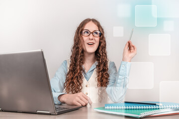 A cheerful young woman at her laptop has a creative idea while working or studying, symbolizing...