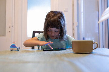 A kid learning how to read on her smart phone.
