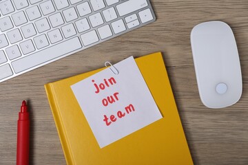 Sticky note with phrase Join Our Team, marker, notebook, computer keyboard and mouse on wooden...