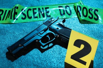 Forensic expertise. Crime scene tape and gun on blue background, closeup. Color toned effect
