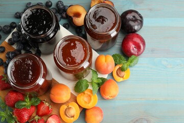 Different jams in jars and ingredients on blue wooden table, flat lay. Space for text