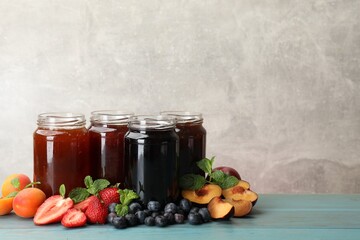 Different jams in jars and ingredients on blue wooden table. Space for text