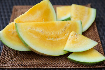 Pieces of ripe yellow watermelon on wicker table, closeup