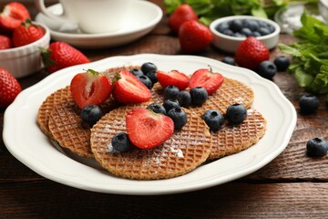 Tasty Dutch waffles (stroopwafels) and berries on wooden table, closeup