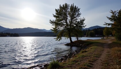 Sunlit Lake Scene with Tree and Mountains in the Background Under Clear Sky
