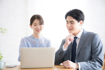 オフィスでパソコンを見るスーツを着たビジネスマン男女　　新人指導やコミュニケーションなどのイメージ