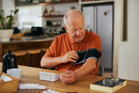 Senior man measuring blood pressure at home