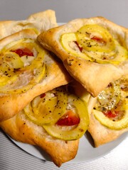 plate freshly baked buns filled with vibrant slices yellow and red vegetables. these delicious pastries offer savory treat perfect for any meal or snack. close up.