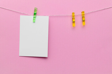 Colorful clips hold a blank note against a pink background for creative displays or reminders