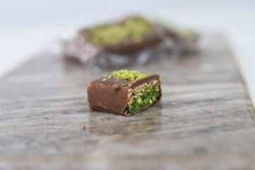 Chocolate Pistachio Bar with Wafer Layers cut in half to showcase its intricate layers with chocolate coating, thin crispy wafer layers, and green pistachio filling side view of sweet treat