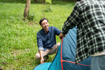 Family bonding during camping. Father and son setting up a tent in the park.