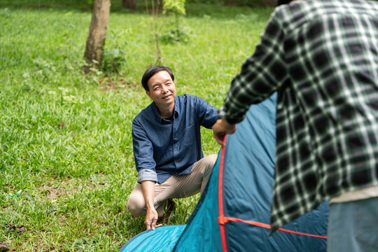 Family bonding during camping. Father and son setting up a tent in the park.