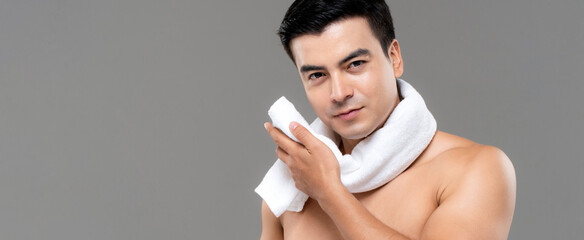 Shirtless man drying face with white towel after workout on gray banner background, men skin care and beauty concept