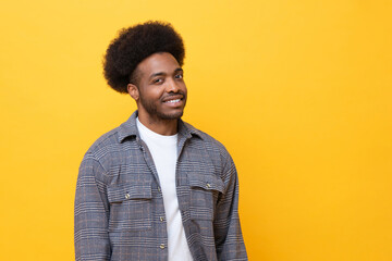 Happy man smiling confidently in casual outfit against yellow background