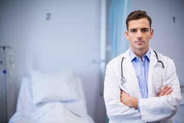 Male doctor wearing lab coat examining bed IV stand privacy curtain using stethoscope, copy space
