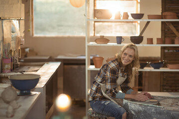 Pottery workshop basking in sunlight at rear window, showing workbench topped with pottery tools