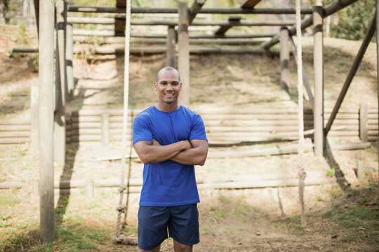 African American man wearing athletic wear standing at park obstacle course with logs and ropes - Powered by Adobe