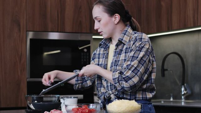 Young woman skillfully prepares delicious dish, cuts cooked meat in modern kitchen