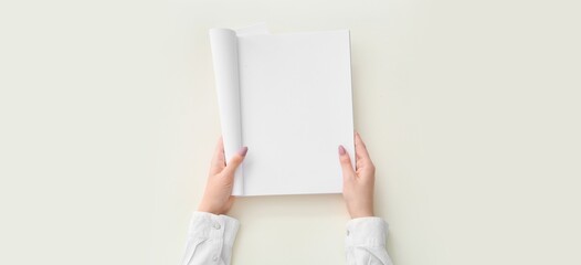Hands holding blank brochure on light background