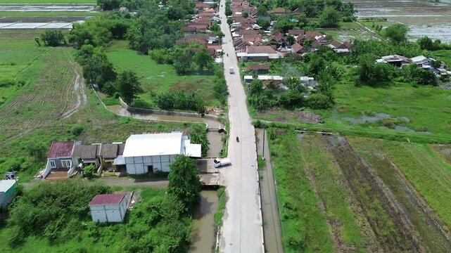 Aerial view from above of rural street and rice field with residentals houses in Mojokerto district, East Java, Indonesia