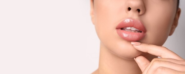 Young woman with beautiful lips on light background with space for text, closeup