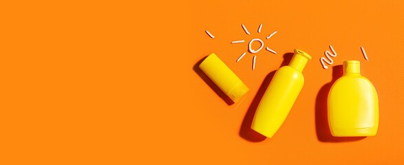 Naklejka na ściany i meble Bottles of sunscreen cream on orange background with space for text