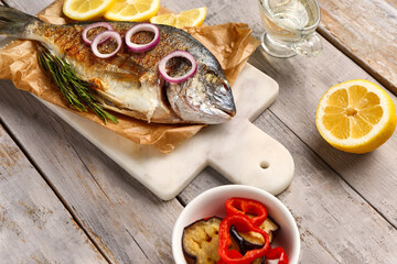 Board with tasty grilled dorado fish on grey wooden background