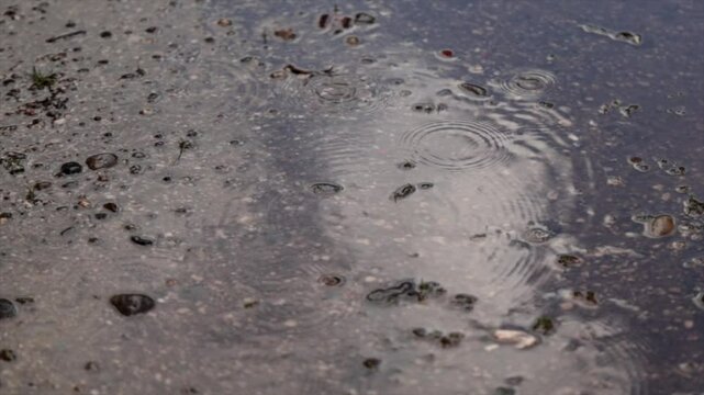 gocce di pioggia che cadono lentamente su un terreno coperto da un sottile strato d'acqua alla fine di un temporale