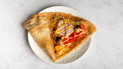 Savory Homemade Mushroom, Spinach and Cheese Crepes on a white plate, side view.