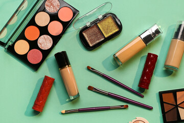 Beautiful palettes of eyeshadows and different decorative cosmetics on green background