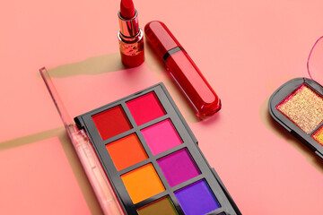 Beautiful palettes of eyeshadows and lipsticks on pink background