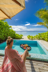 Stunning sexy woman enjoying floating breakfast in private villa infinity pool view. Luxury beach...