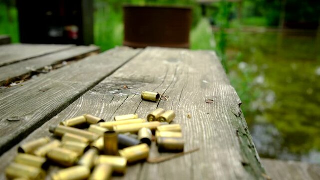 Slowly moving camera backward and close up of empty bullet shells laying on the old wooded table after hunting or shooting practice
