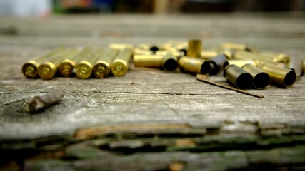 Slowly moving camera up revealing empty bullet shells laying on old wooden table after hunting or shooting exercise