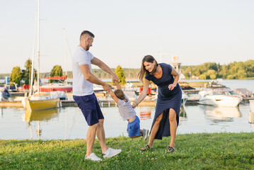 Obraz premium Pregnant Mother and Father Playing With Child Together Outdoors