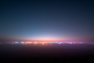 Fototapeta premium Distant city lights at twilight hazy skyline