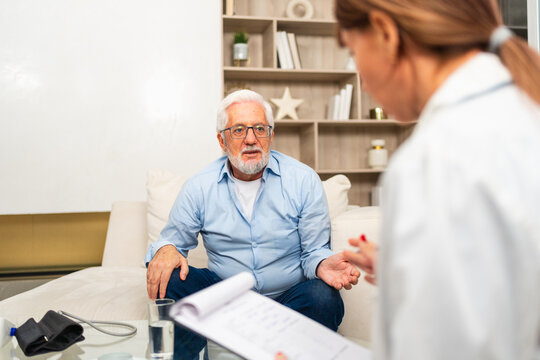 Female doctor examining older senior man in doctor office or at home. Old man patient and doctor have consultation in hospital room. Medicine healthcare medical checkup. Visit to doctor
