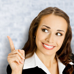 Portrait image - happy smile businesswoman show pointing advertise free ad text space. Business woman executive employee bank manager, teacher on white bricks loft wall background. Square