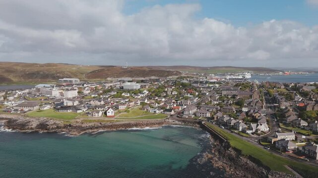 An aerial shot of the harbour town of Lerwick, Shetland in Scotland, with the blue water coastline.