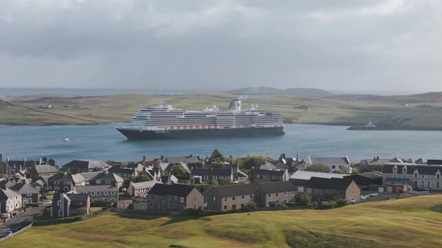 A huge cruise ship destroying the landscape of a residential town in Lerwick, Shetland in Northern Scotland, showing the impact of Cruise ships on local destinations.
