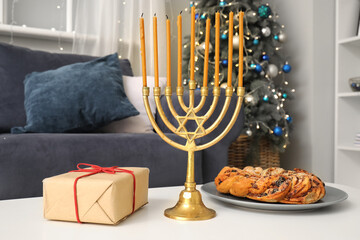 Coffee table with menorah, gift box and traditional babka in living room. Hanukkah celebration