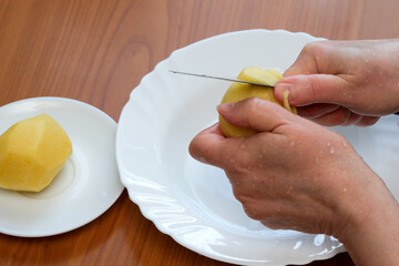 Peeling a potato with precision at a kitchen table in the afternoon