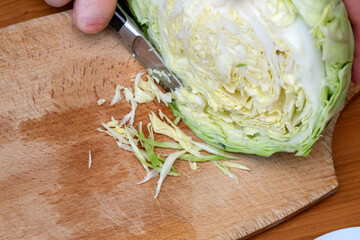 Chopping fresh cabbage on a wooden board for healthy meal preparation