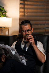 Businessman holding a glass of whiskey, sitting and drinking in a room